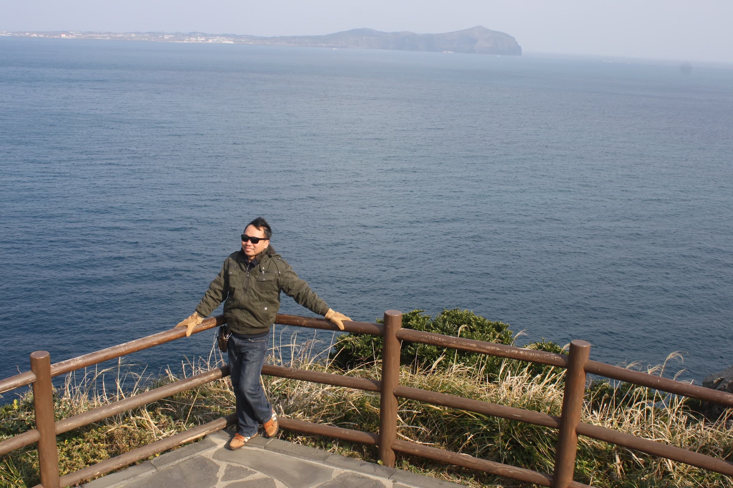 Papi berpose di depan pemandangan laut saat berwisata di Korea