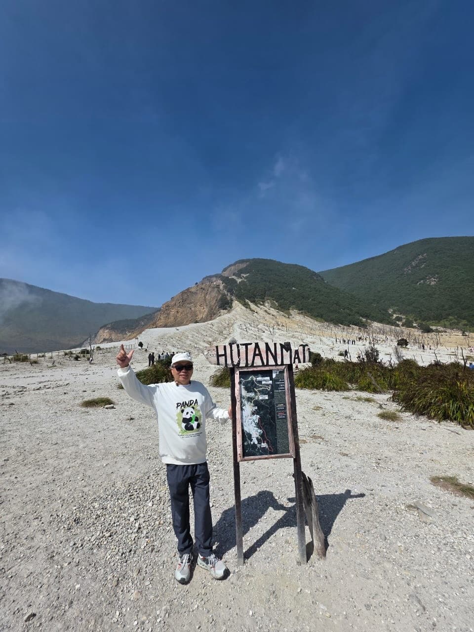 Papi berfoto di Hutan Mati dengan pemandangan gunung
